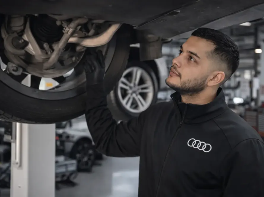 Mecânico especialista Audi inspecionando suspensão e parte inferior de veículo Audi elevado na rampa da oficina Premium Car em Porto Alegre