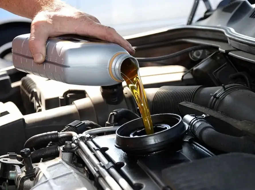 Mão realizando troca de óleo lubrificante dourado despejado diretamente no motor de veículo Mercedes-Benz na oficina especializada Premium Car em Porto Alegre