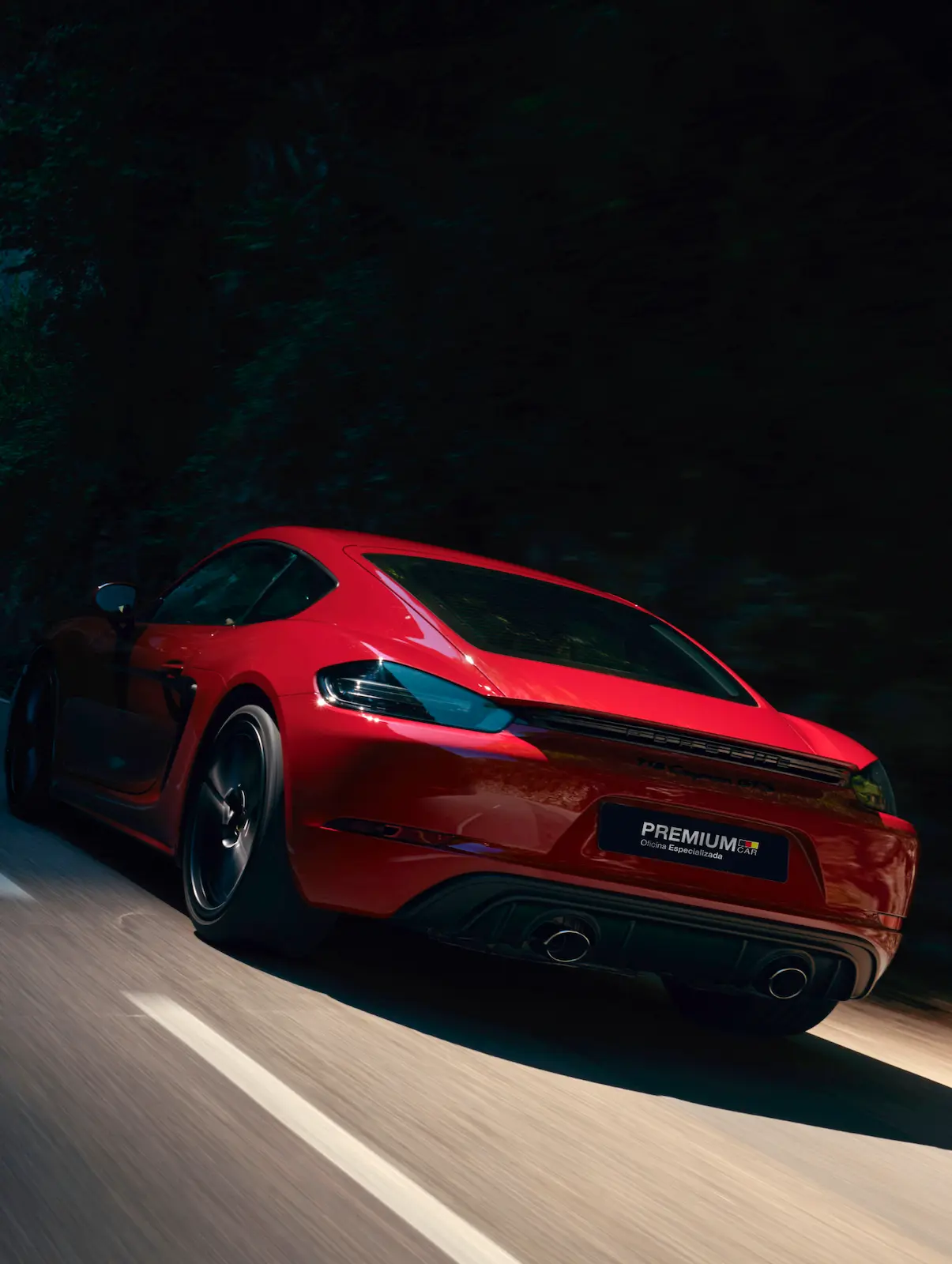 Porsche 718 Cayman GTS 4.0 vermelho traseira em movimento à noite em estrada com árvores, com logo Premium Car Oficina Especializada em Porto Alegre