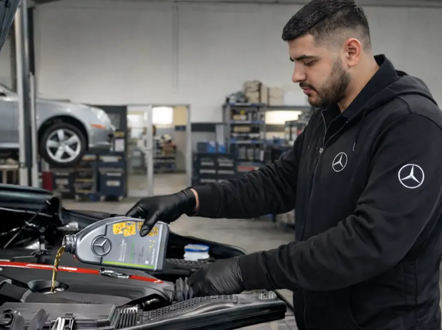 Mecânico especialista com uniforme Mercedes-Benz despejando óleo lubrificante Mercedes no motor de veículo com capô aberto na oficina Premium Car em Porto Alegre